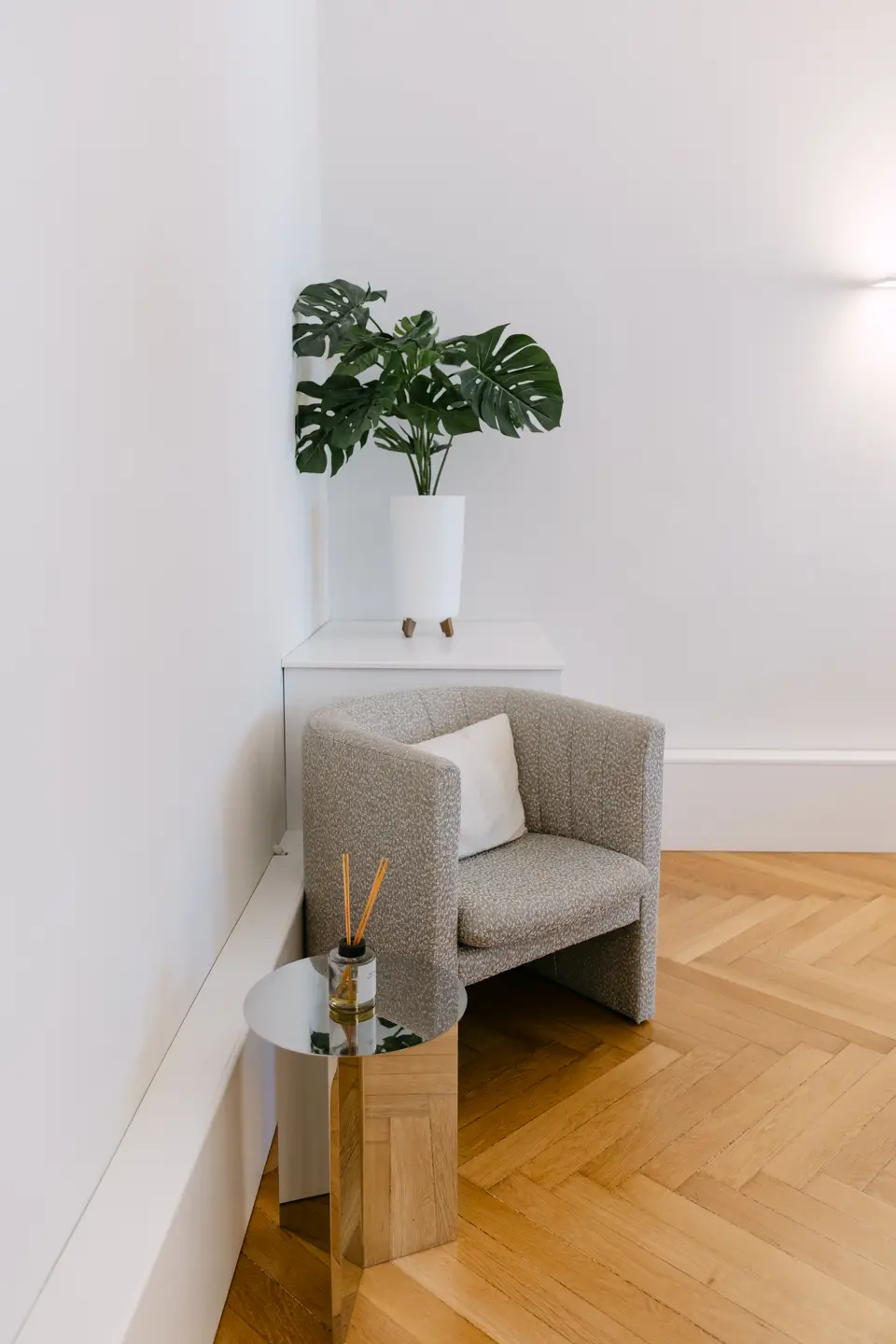 Sitzecke mit gemustertem Sessel, einer Monstera und einem kleinen Beistelltisch
