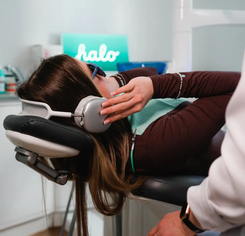 Patientin mit Kopfhörern und Schutzbrille im Behandlungsstuhl